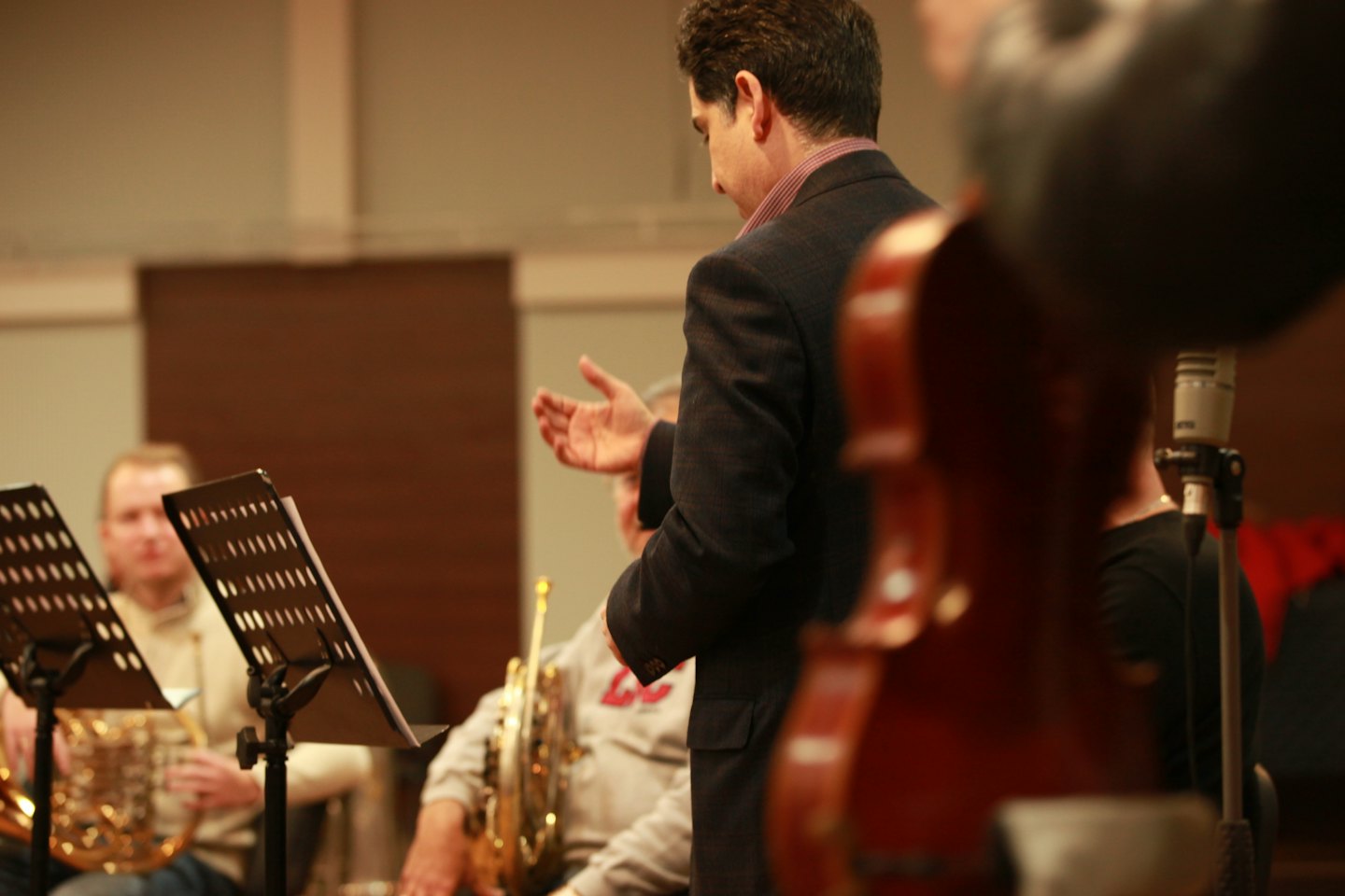 Un director de orquesta hace gestos a los músicos durante un ensayo.