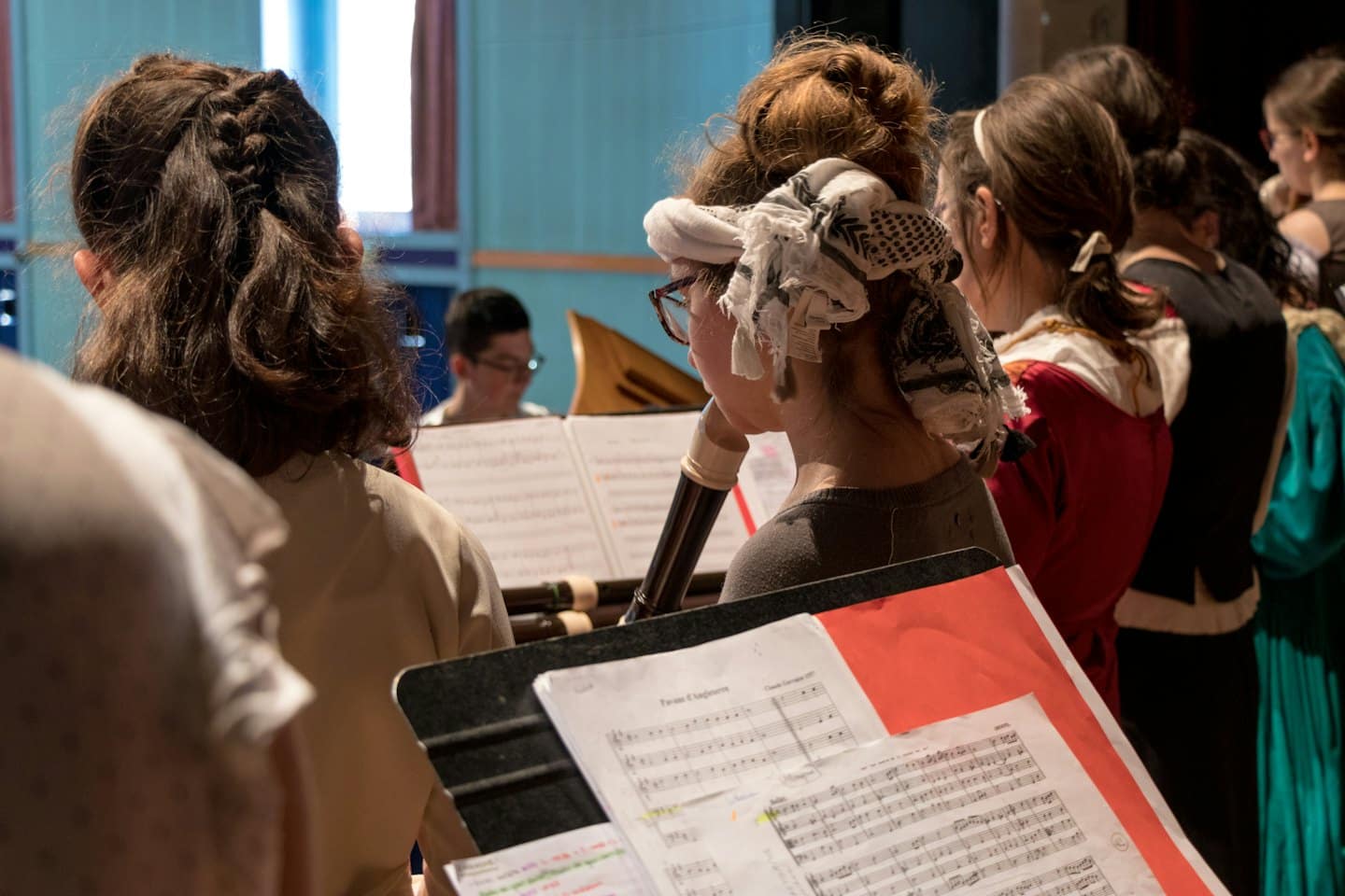 Músicos tocando flautas dulces y sosteniendo partituras durante un ensayo.